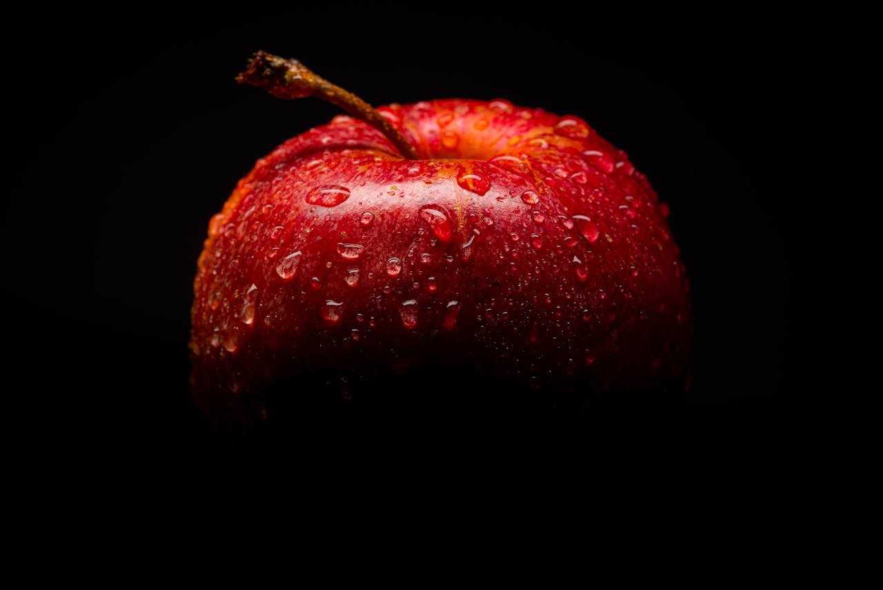 services-01 Close-up of a fresh red apple with water droplets against a dark background.
